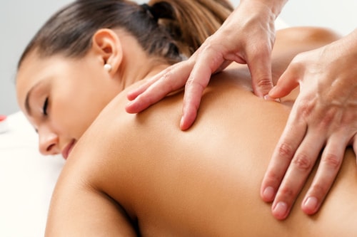 Une masseuse masse le haut du dos de sa cliente.