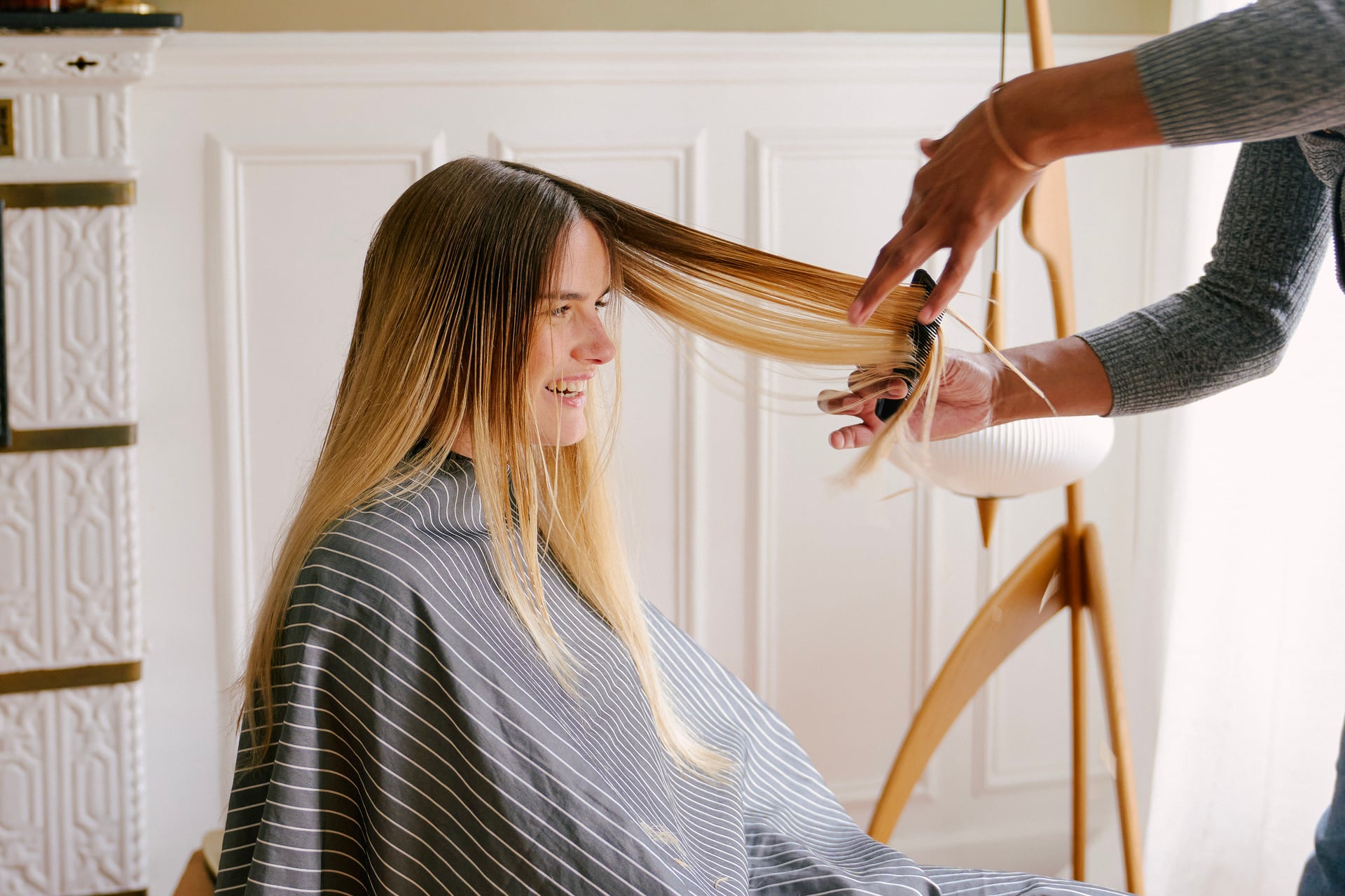 Une coiffeuse à domicile en train de couper les cheveux d'une cliente