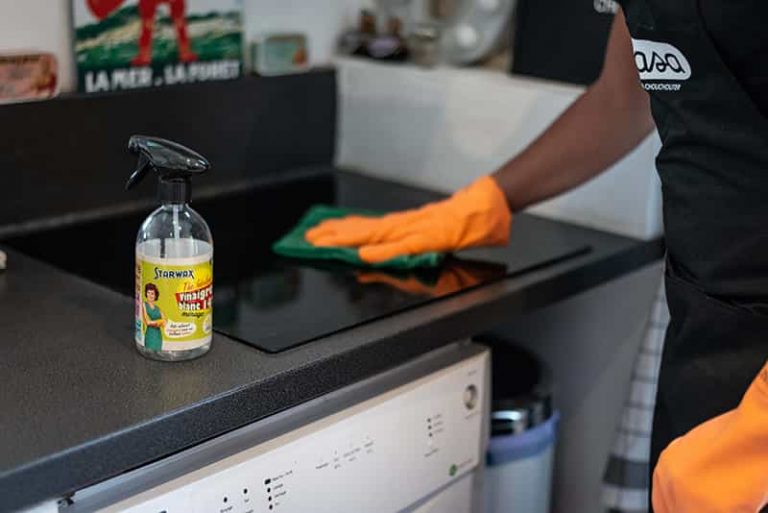 Un homme de ménage Wecasa utilise un produit de nettoyage sur une plaque de cuisson