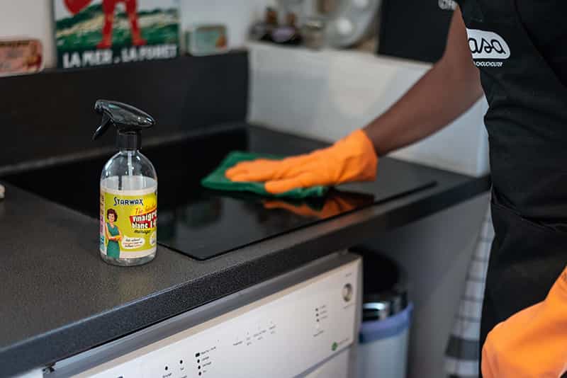 Un homme de ménage Wecasa utilise un produit de nettoyage sur une plaque de cuisson.