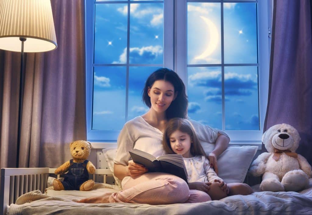 La nounou lit une histoire à une petite fille dans sa chambre avant de la coucher