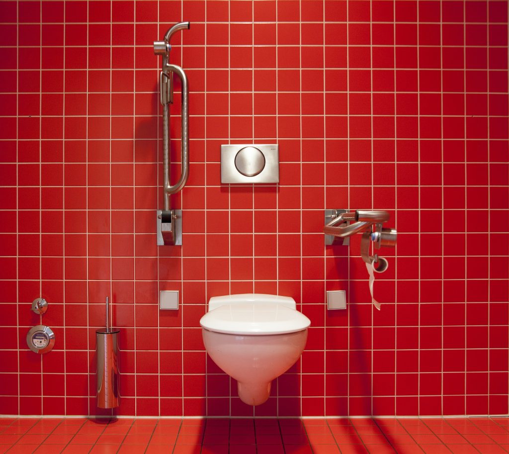 Toilettes et douche très entartrés dans la salle de bains sur un mur en carrelage rouge