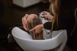 une femme se fait décolorer les cheveux dans un salon de coiffure