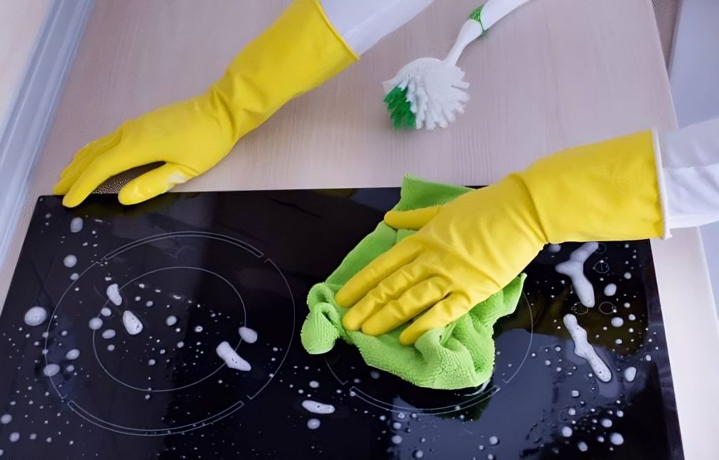 Femme de ménage nettoyant une plaque en vitrocéramique