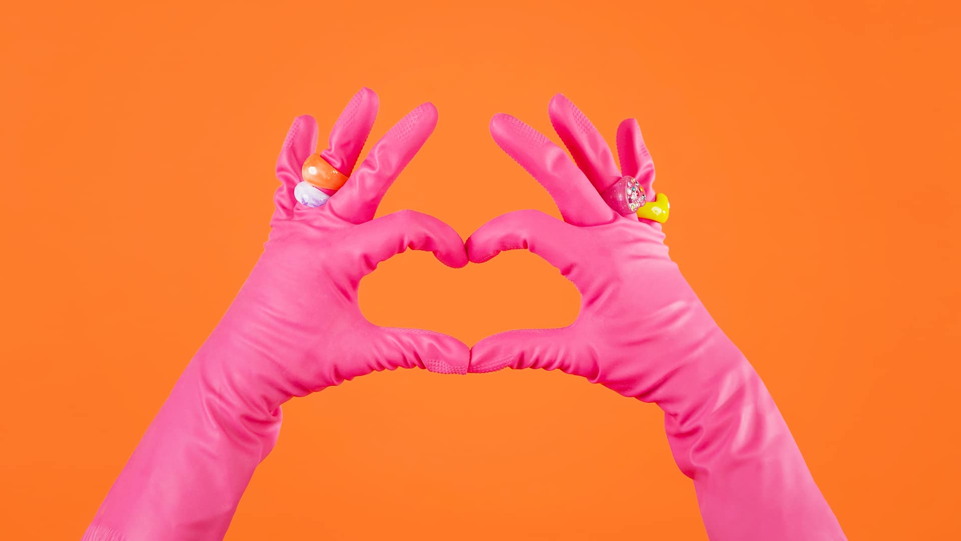 Une femme de ménage portant des gants fait un coeur avec ses mains