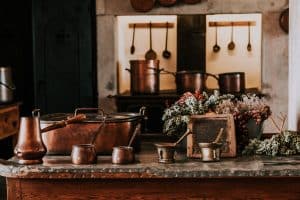 Une cuisine avec des casseroles et ustensiles en cuivre au premier plan.