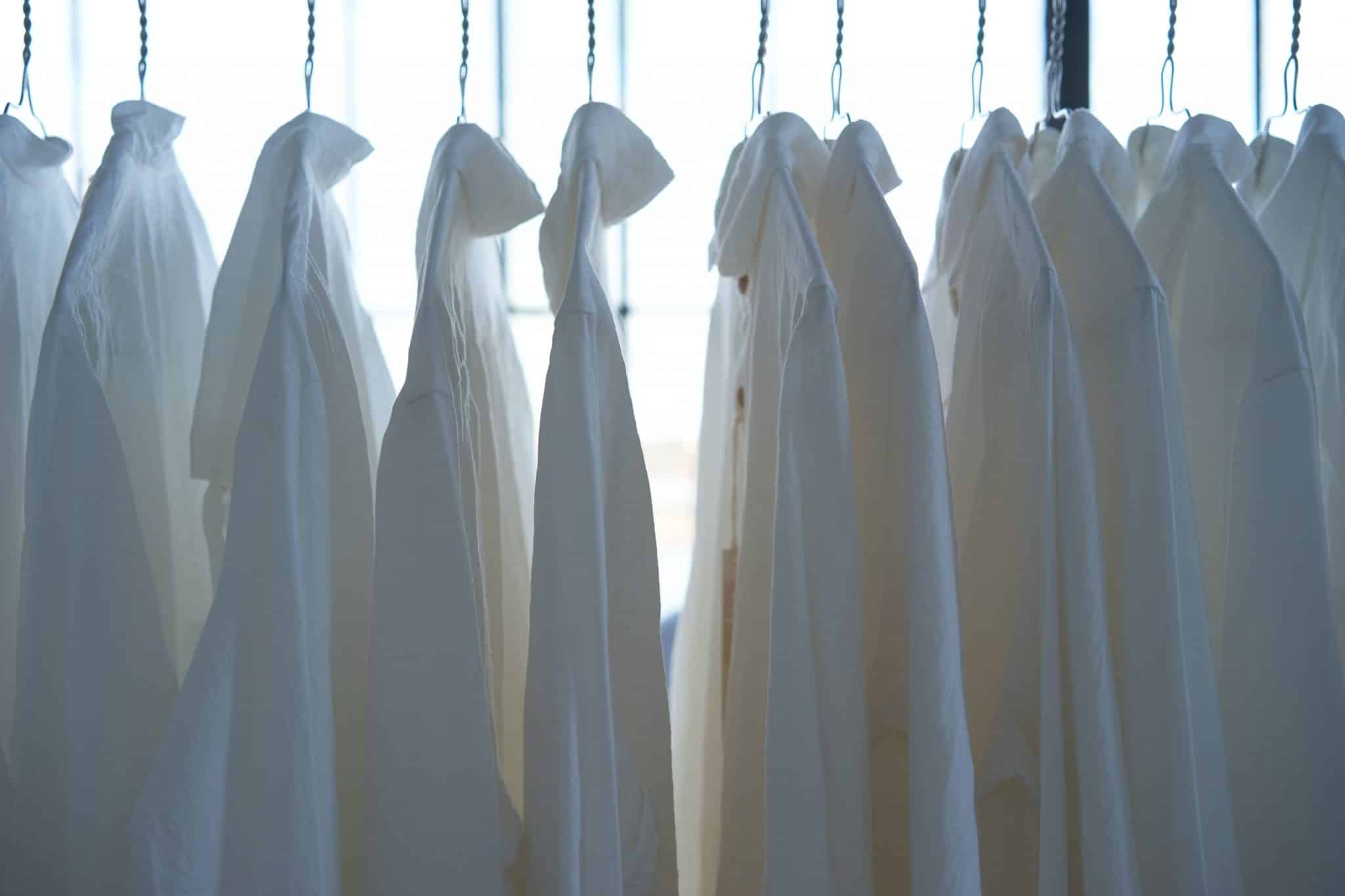 Des chemises blanches sont accrochées à des cintres
