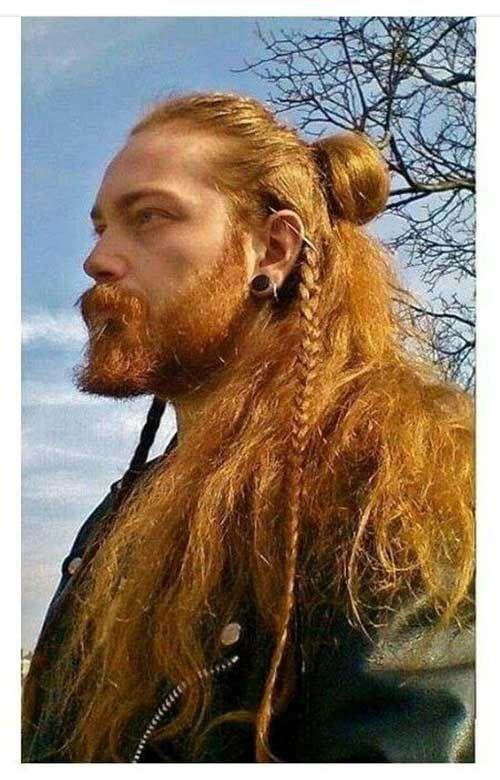 Un homme avec une coupe viking comprenant barbe, cheveux longs, chignon, tresses