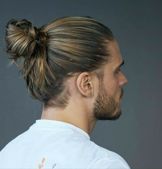 Un homme avec une coupe viking chignon (man bun)