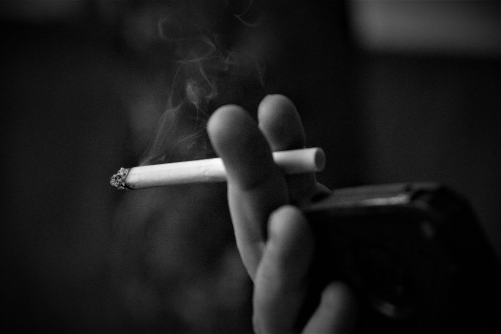 Cigarette in darkness on black background-how to get rid of the smoke smell in your house