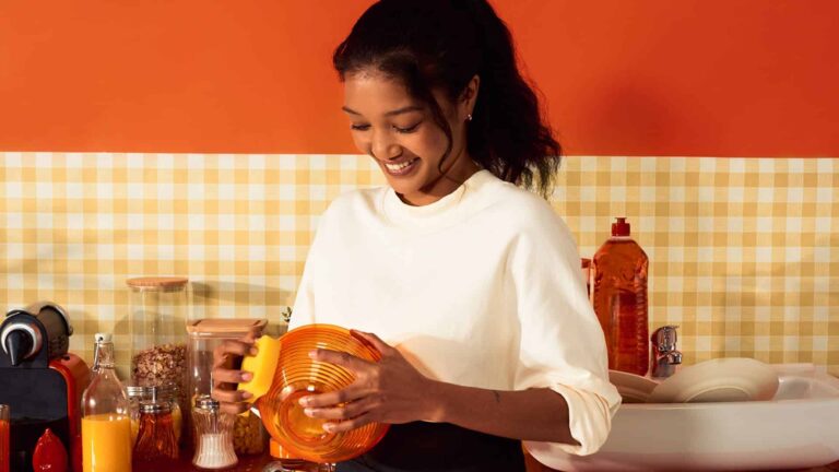 femme nettoyant le moisi accumulé sur les joints du carrelage sur le mur de la salle de bains