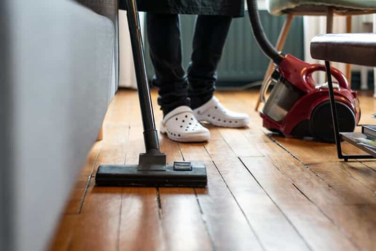 image d une aide menagere passant l'aspirateur sur un parquet ancien